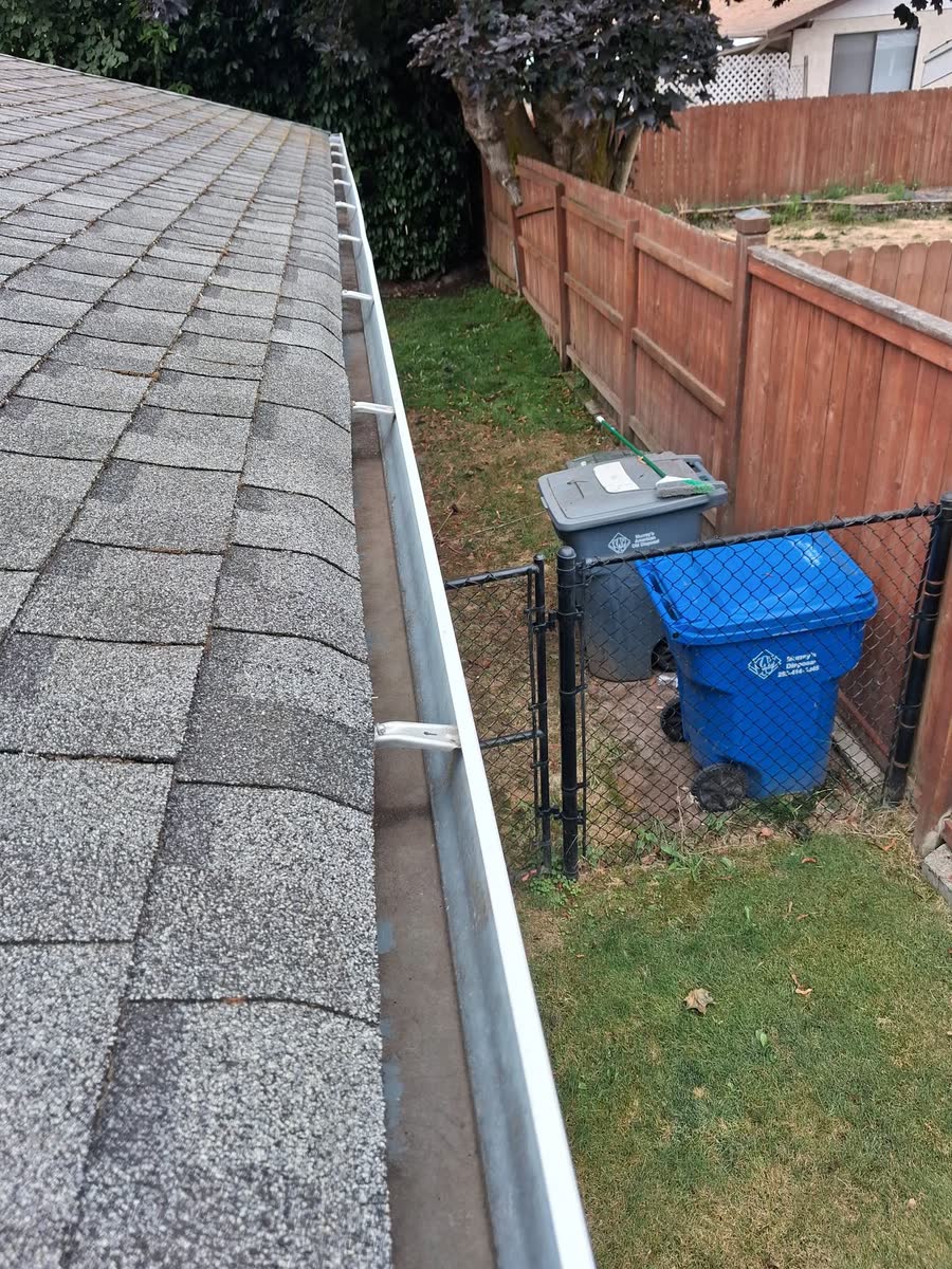 A clean gutter along a roof edge above a fenced side yard.