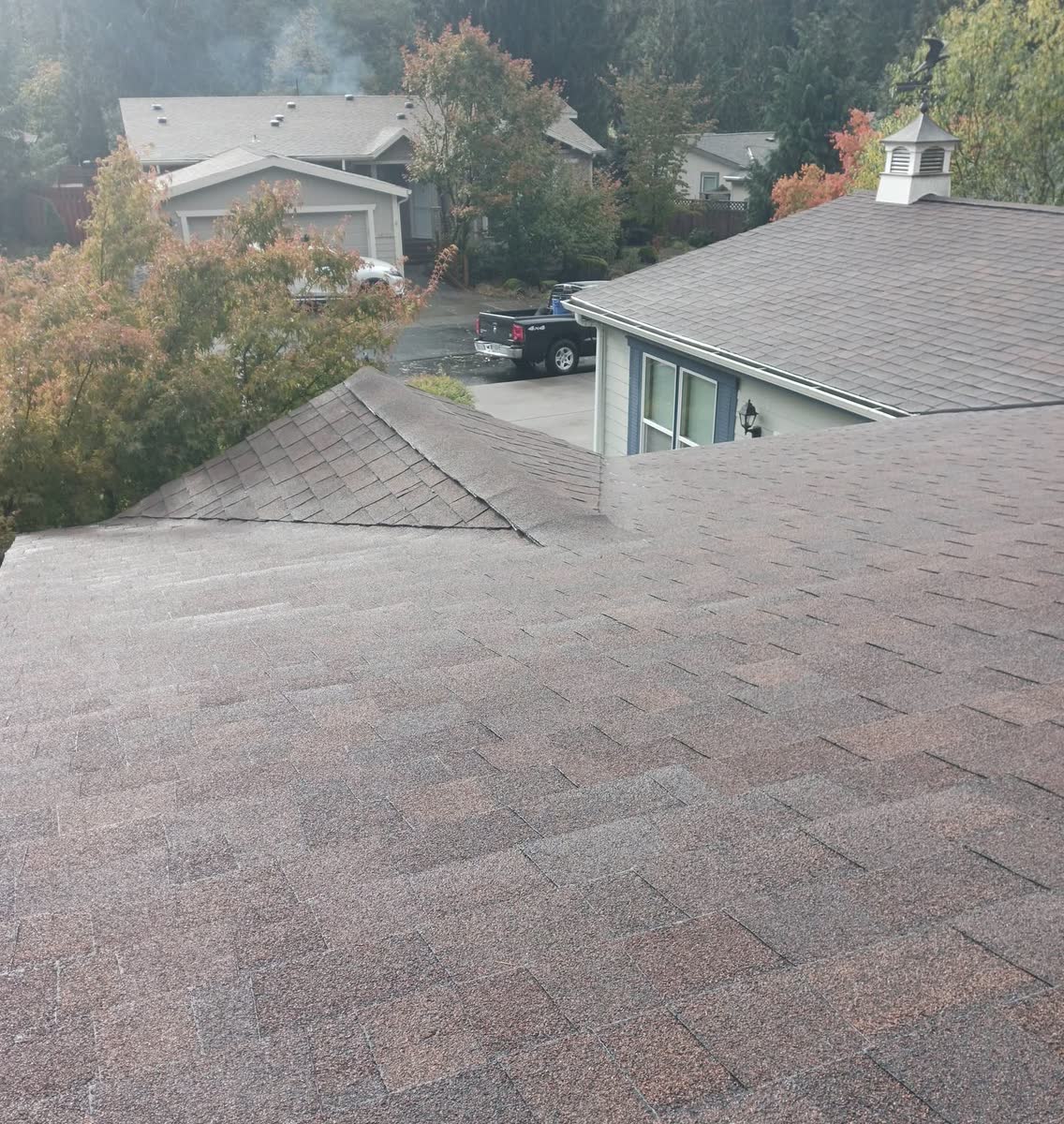 A clean shingle roof seen from the top, neighbouring roofs beyond.