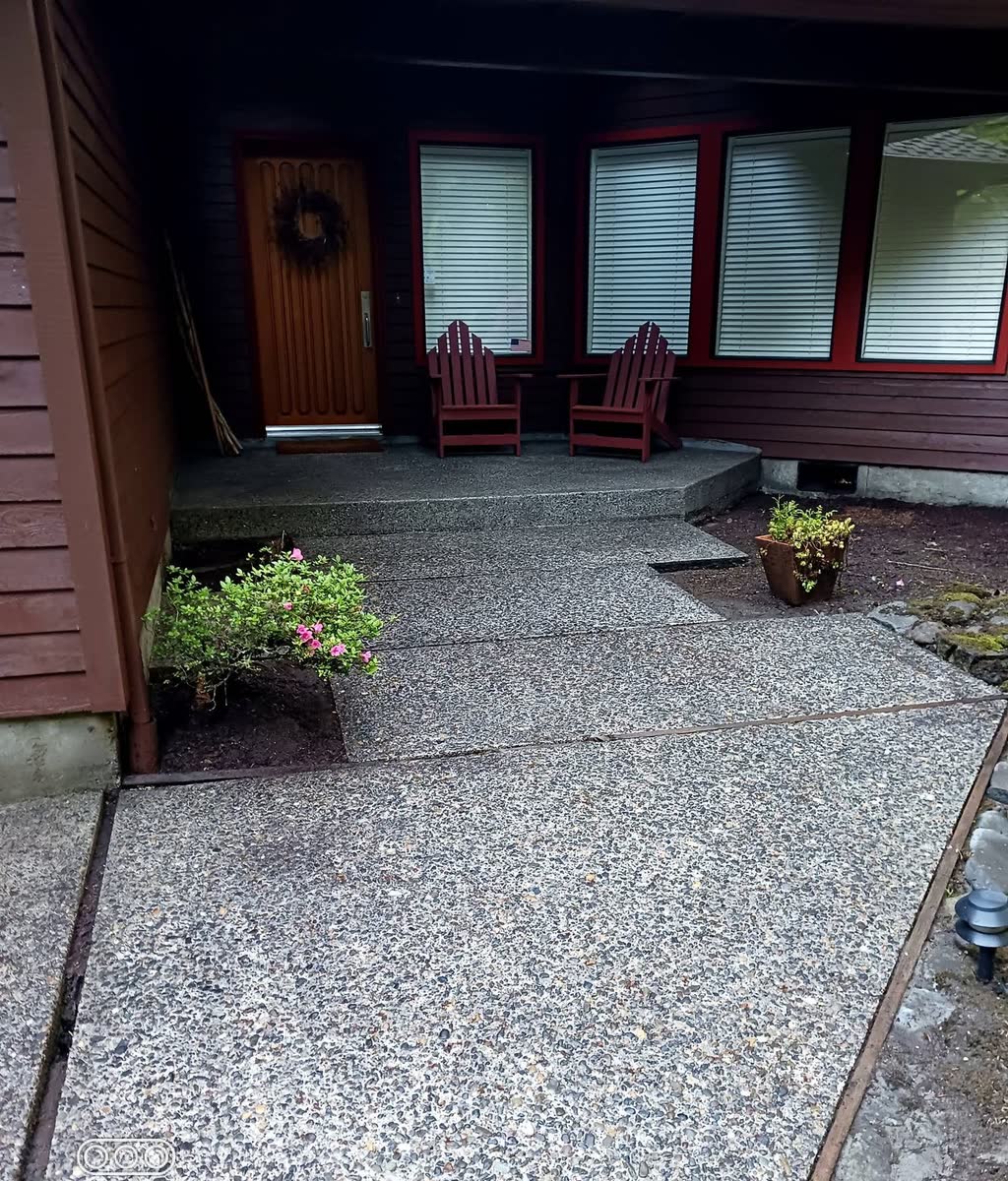 A front walkway and step pressure washed clean, two red chairs on the porch.